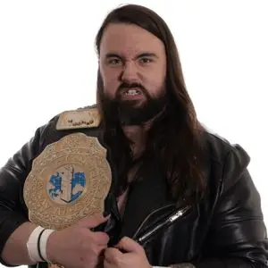 David grant with long dark hair and beard stands with an aggressive expression while holding the WIN Wrestling Heavyweight Title over his right shoulder.