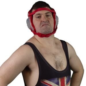 Ben Shelly is wearing red amateur wrestling head gear with clear ear protectors and a singlet with the union jack flag on the front