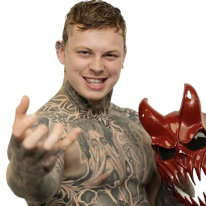 Alister Sixx reaches out to the camera with one hand holding his trademark horned devil type mask in the other