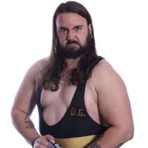 David stands in a black gold and green singlet pulling an agressive face while holding a can of drink and flexing his muscles.