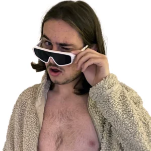 Elliot poses peering over white rimmed sunglasses while wearing a sheepskin jacket